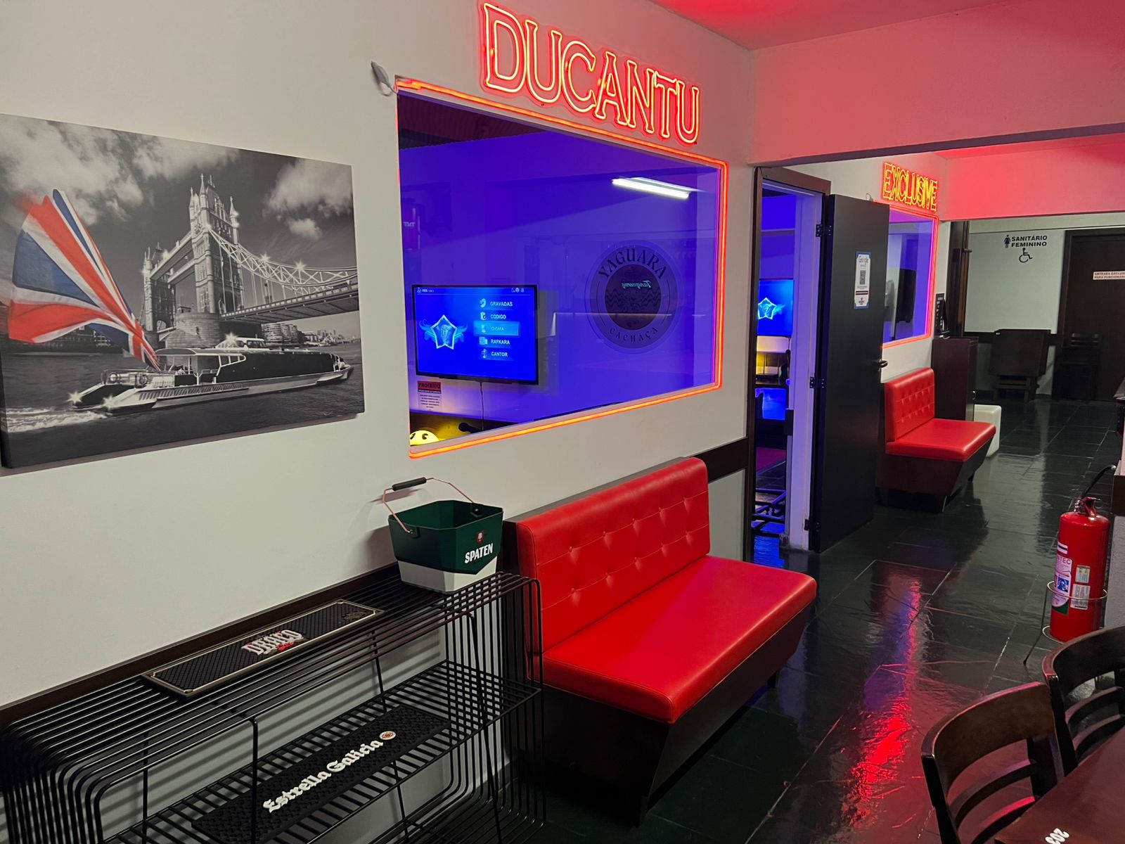 Corredor com o nome Ducantu em neon vermelho e sofá vermelho