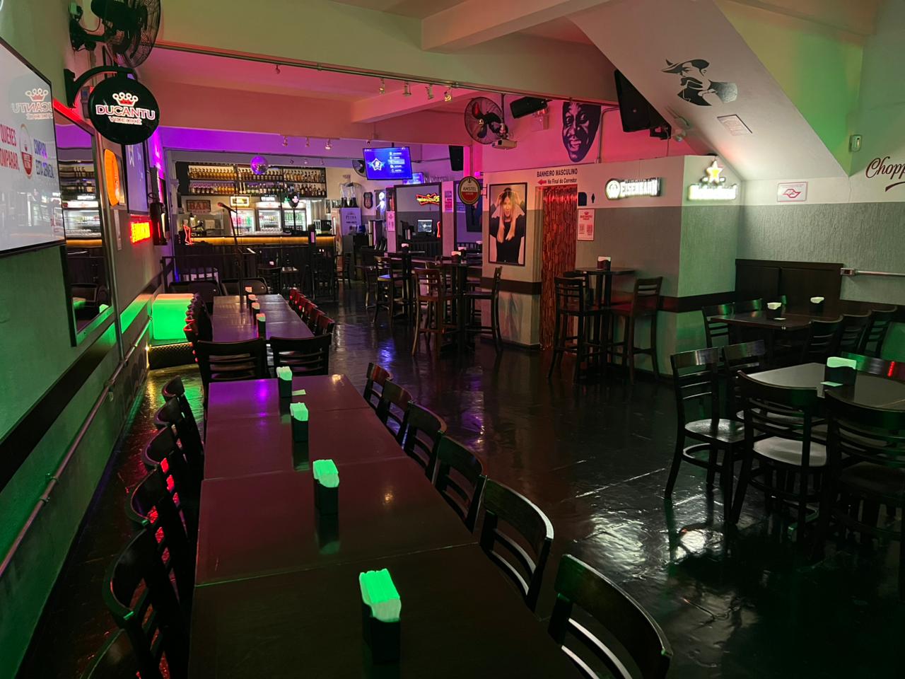 Salão interno com mesas e iluminação colorida